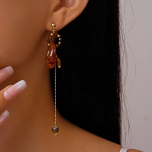 Detail of amber resin teardrop earring with beaded ring and golden chain on model