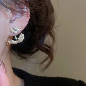 Close-up of gold-plated leaf earring with sparkling zircons worn by model on ear