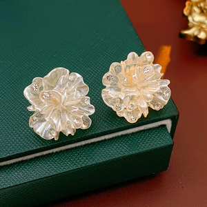 Gros plan de boucles d'oreilles fleur dorées avec cristaux sur une boîte à bijoux verte