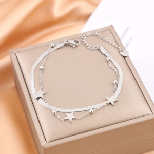 Elegant silver double-layer chain bracelet featuring star charms on a luxury jewelry box