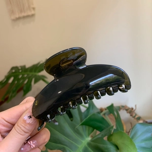 Detail of a large translucent dark green hair claw clip with a glossy acetate finish