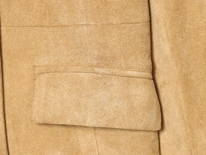 Vue macro de la texture en daim camel et des coutures de précision sur la veste