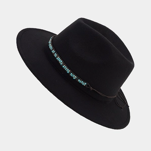 Détail du chapeau fedora en feutre noir avec ruban décoratif tissé bleu et doré