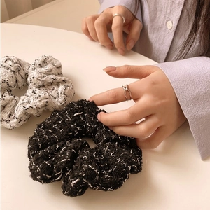 Close-up of the black and white tweed fabric texture on a thick elastic scrunchie