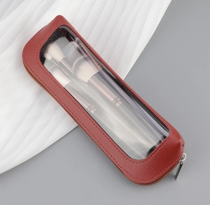 Detail of red leather makeup bag with transparent window and silver zipper pull