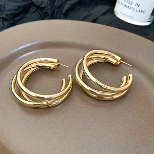 Detail shot of triple gold layered hoop earrings on an elegant display base