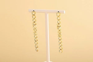Detail of long gold chain earrings with LOVE letters on a professional T-stand