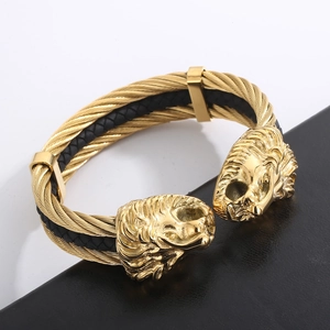 Macro detail of golden lion head charm on black braided cable bangle for men