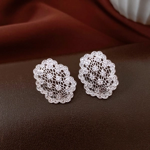 Macro shot of silver hollow oval earrings with white zircon pave in French retro style