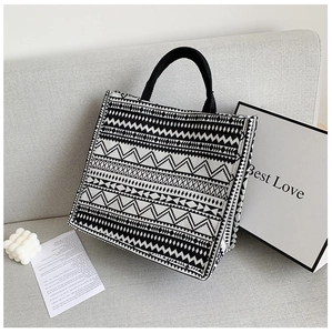 Detail shot of geometric canvas tote bag on a grey sofa with minimalist decor props