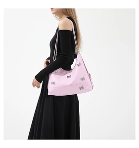 Close-up of pink nylon shoulder bag featuring decorative silver butterfly accents on the strap