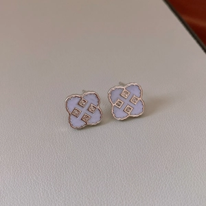 Detail view of light blue clover stud earrings with silver edges on a leather texture