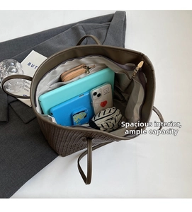 Spacious interior of brown woven tote bag showing tablet, phone, and folding umbrella