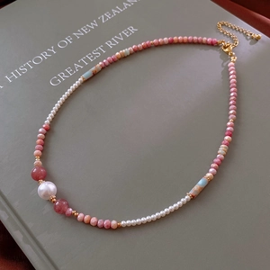 Detailed close-up of natural pearl and strawberry quartz beaded necklace on book