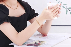 Ensemble collier et bracelet à maillons dorés porté par un mannequin dans un cadre moderne