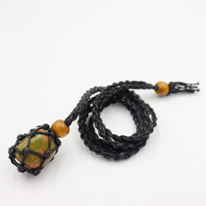 Macro shot of green and orange unakite stone in black handmade woven net cord necklace