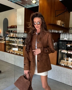 Close-up of brown suede jacket with large buttons and flap pockets in a cafe setting