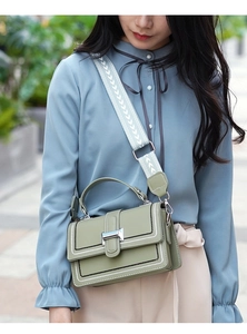 Detail of olive green handbag with contrast stitching and wide herringbone strap