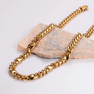 Chunky gold stainless steel Cuban link chain necklace on a decorative stone base