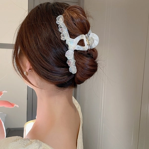 Gros plan sur une pince à cheveux géométrique aux reflets nacrés tenant un chignon chic