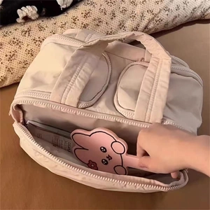 Top view of beige large capacity makeup bag with wide opening and dual handles in use