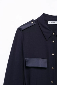 Detailed macro view of navy blue cargo dress showing satin shoulder tabs and gold buttons