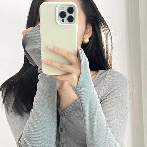 Close-up of matte golden ball earrings paired with a gray ribbed knit sweater