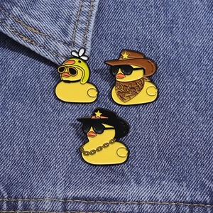 Trois pin's canards jaunes mignons avec lunettes et chapeaux sur tissu en jean