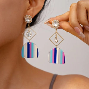 Detail of trendy resin dangle earrings with colorful stripes and geometric crystal charms