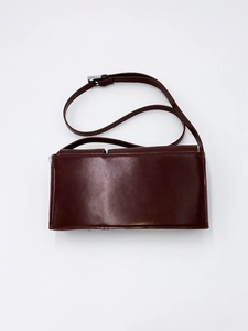 Detailed view of dark coffee leather baguette bag with silver metal buckle and strap