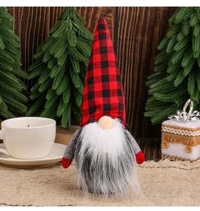 Close-up of a Christmas gnome doll with red and black plaid hat on a festive wooden table
