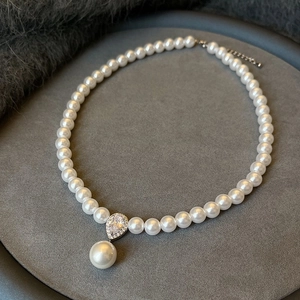 Dettaglio macro della collana di perle con pendente a goccia di diamante su velluto