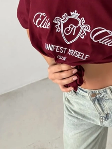 Gros plan détaillé de la broderie du logo blanc sur un t-shirt oversize bordeaux