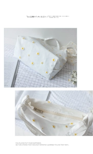 Detail view of white canvas tote bag with daisy embroidery and metal zipper closure