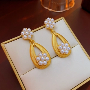 Close-up of vintage gold earrings with pearl flower design in a luxury jewelry box