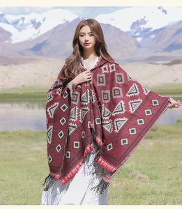 Vue détaillée d'un poncho ethnique rouge à motifs géométriques et franges noires
