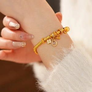 Detail of 24k gold plated clover charm and oval zircon pendant on a snake bone chain