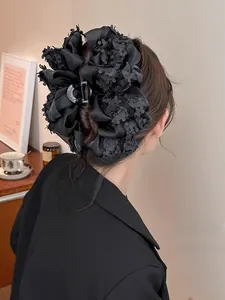 Détail d'une grande pince à cheveux fleurie en velours noir multicouche et résille