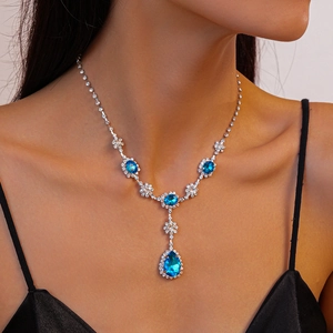 Gros plan d'un collier argenté vintage avec des pendentifs en cristal bleu goutte et ovale