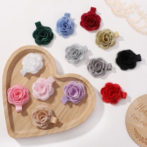 Close-up of handmade fabric rose hair clips in diverse colors on a heart wooden tray