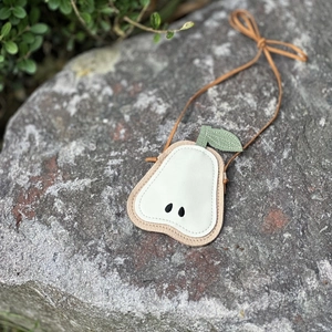 Detailed view of children's pear-shaped crossbody bag with leaf detail on a natural stone