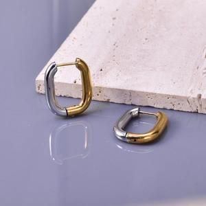 Modern two-tone U-shape stainless steel earrings on a minimalist stone display
