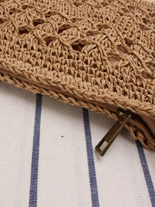 Handcrafted hollow straw woven crossbody bag with detailed brown zipper and summer texture