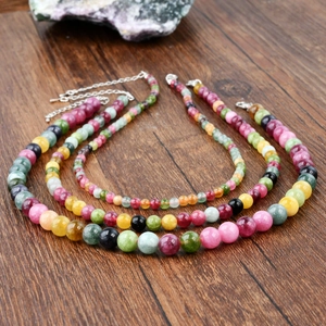 Three vintage multi-color tourmaline beaded necklaces on a rustic wooden surface