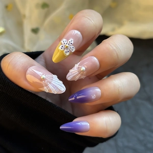 Detail of almond-shaped press-on nails with 3D floral, pearl accents and shell texture