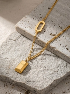 Detailed macro view of 18k gold plated bar pendant with LOVE engraving on stone surface