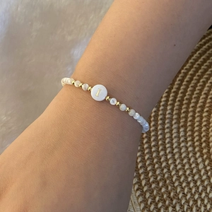 Detailed shot of beaded letter I bracelet with pearls and golden accents on model