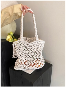 Detail of handmade hollow woven cream tote bag with tassels and cotton rope texture
