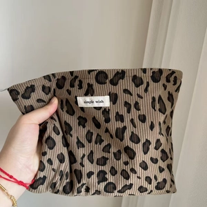 Détail d'une trousse à maquillage en velours côtelé léopard avec étiquette tissée