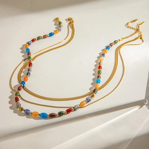 Detail of gold double-layered necklace featuring a flat snake chain and colorful stone beads